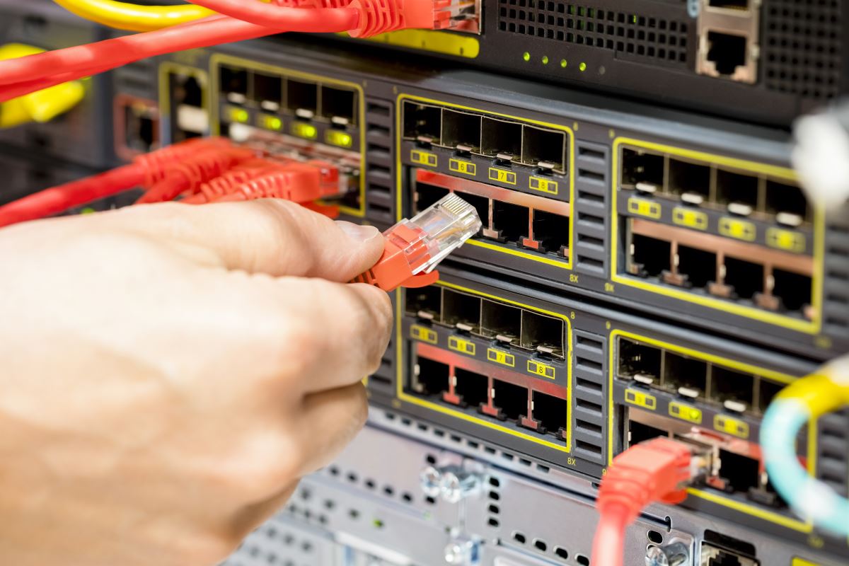 hand plugging fiber cable into switch in datacente 2023 11 27 05 06 57 utc